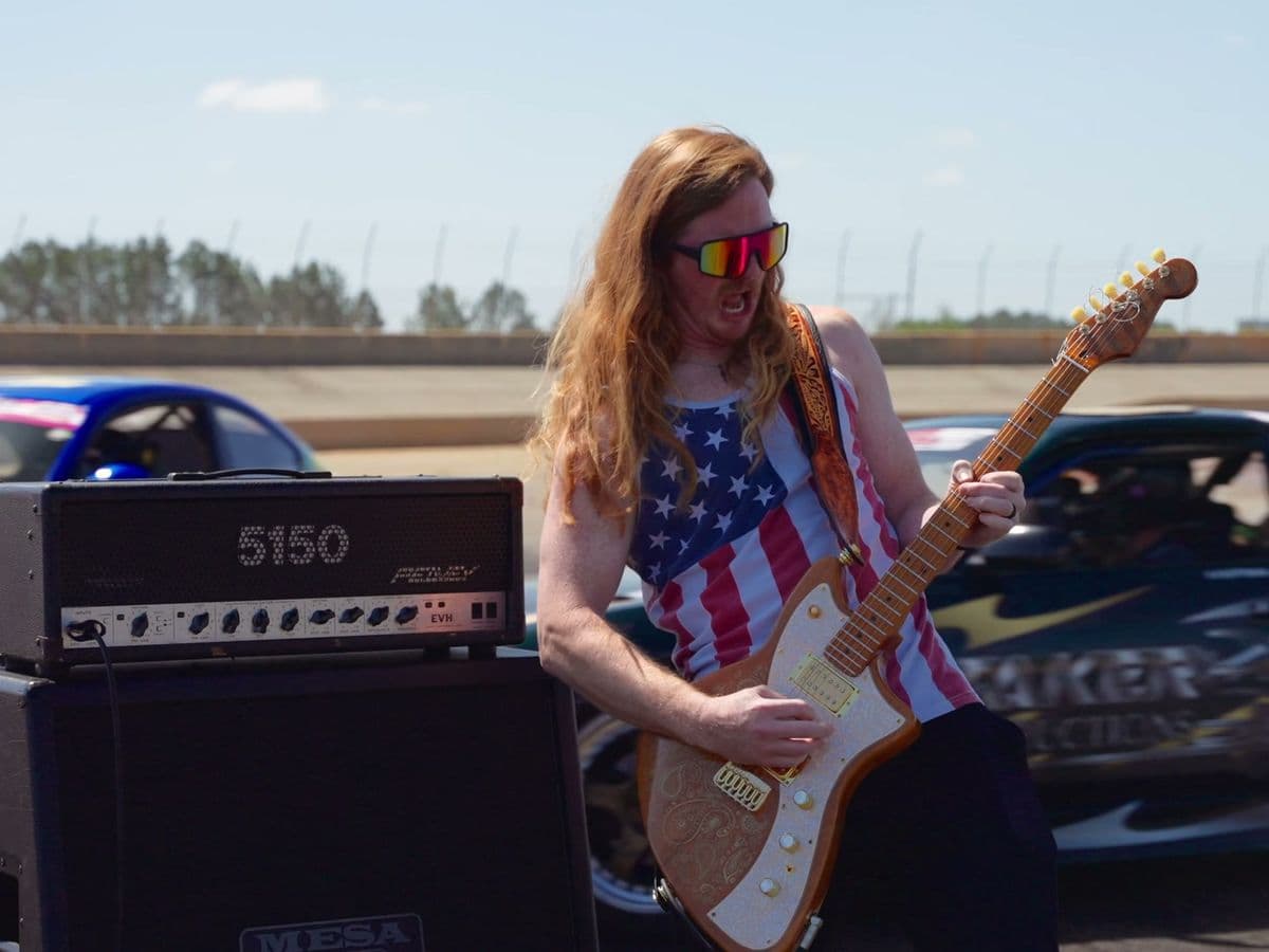 Guitar amp stacks staged on the strip with a race car behind